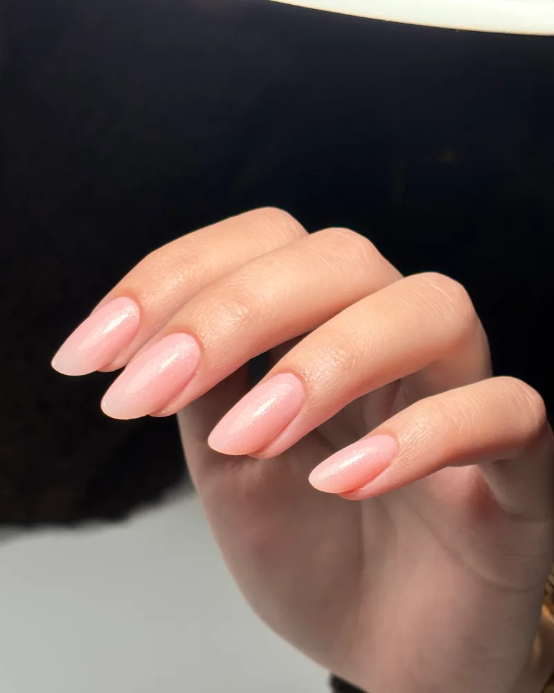 Pose gel nude nacrée sur ongles amande longs, lumière rasante