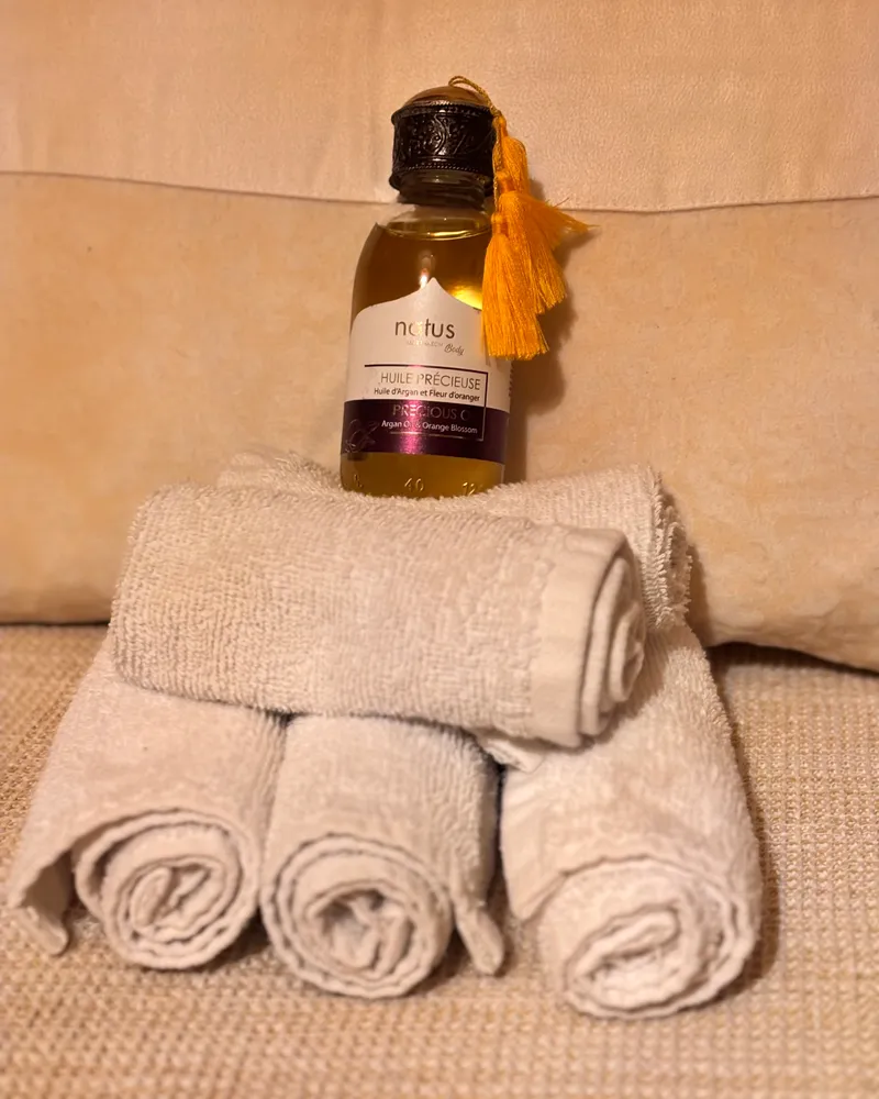 L'huile précieuse à l'argan et à la fleur d'oranger, posée sur les serviettes du soin